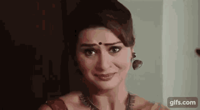 a close up of a woman wearing a yellow saree and earrings .
