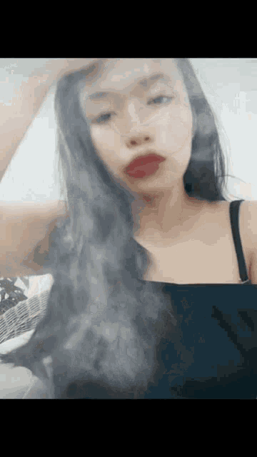 a woman with long black hair is wearing a black tank top