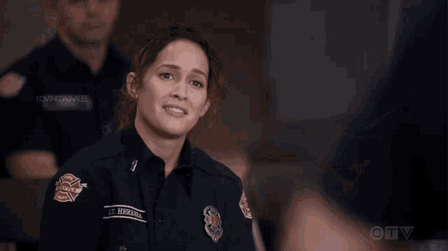 a woman in a firefighter uniform is smiling in front of a ctv screen