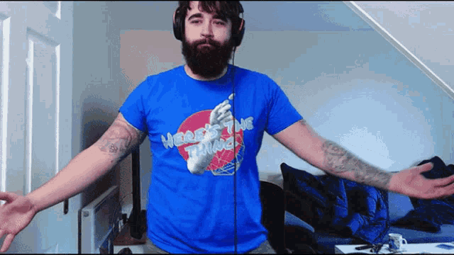 a man wearing headphones and a blue shirt that says " here comes the thing "