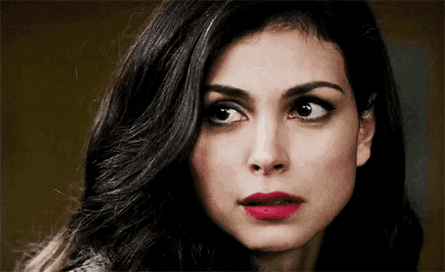 a close up of a woman 's face with long black hair and red lipstick .