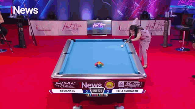 a woman is playing pool on a pool table sponsored by the news