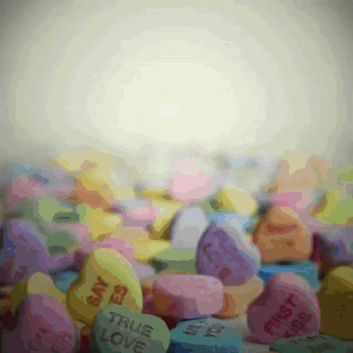 a pile of heart shaped candy with one saying true love