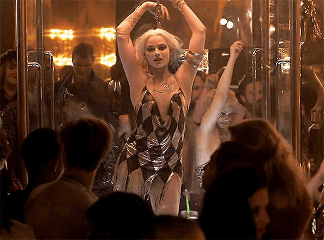 a woman in a harlequin dress is dancing in a crowded room
