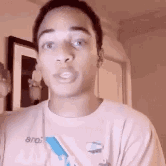 a young man is making a funny face while wearing a pink t-shirt .