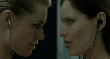 two women are kissing while wearing headphones and listening to music .