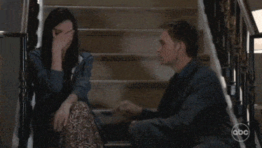 a man and a woman sit on a set of stairs with the abc logo on the bottom