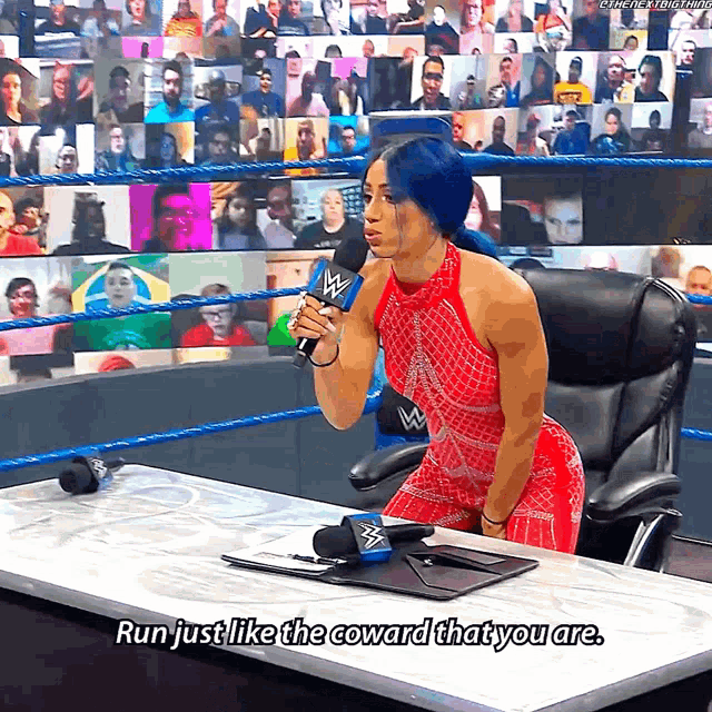 a woman in a red dress is talking into a microphone with the words run just like the coward that you are below her