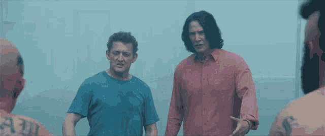 a man with a tattoo on his back stands next to a man in a red shirt