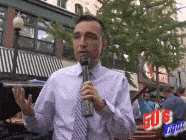 a man holding a microphone in front of a 50 's night logo