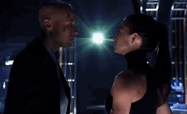 a man and a woman are looking into each other 's eyes in a dark room