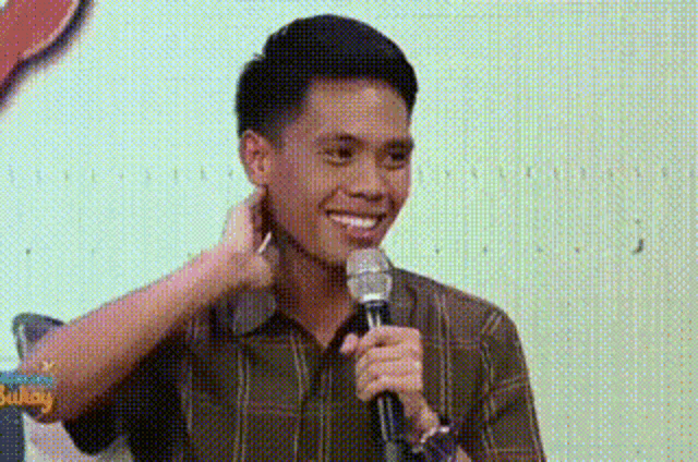 a man is holding a microphone and smiling while a woman touches his neck .