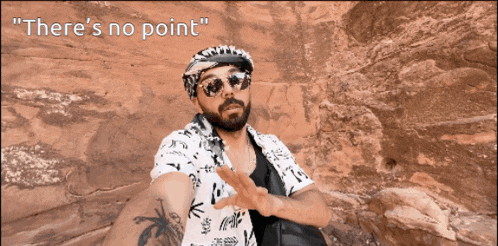 a man wearing sunglasses and a bandana says " there 's no point " in front of a rocky landscape
