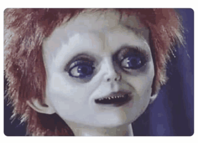 a close up of a creepy doll 's face with red hair .