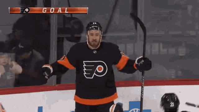 a group of hockey players are celebrating a goal during a game against the flyers