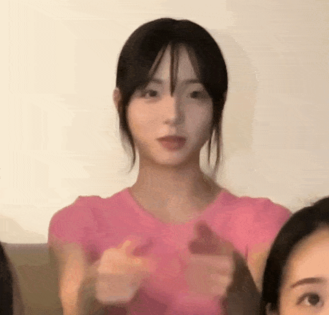 a woman in a pink shirt is giving a thumbs up sign while sitting next to another woman .