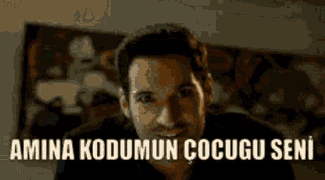 a man in a black shirt is smiling with the words amina kodumun cocugu seni above him
