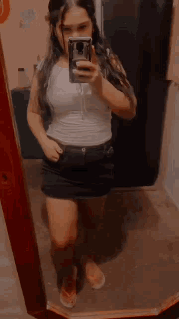 a young woman is taking a selfie in front of a mirror .