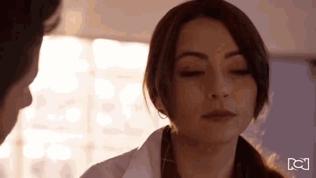 a woman in a white lab coat is looking at a man with her eyes closed and her mouth open .