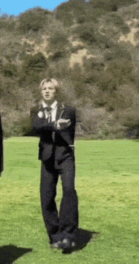 a man in a suit is standing in a grassy field .