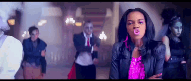 a woman in a pink top is standing in front of a group of people dressed in costumes .