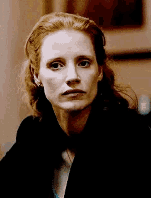 a close up of a woman 's face with red hair and a serious look on her face .