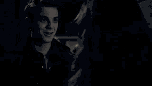 a man and a woman are standing next to each other in a dark room and smiling at each other .