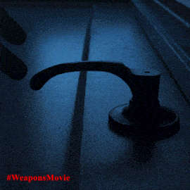 a person 's hand is reaching for a door handle in the dark