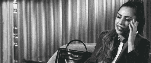 a woman is sitting on a couch with a purse and talking on a cell phone .