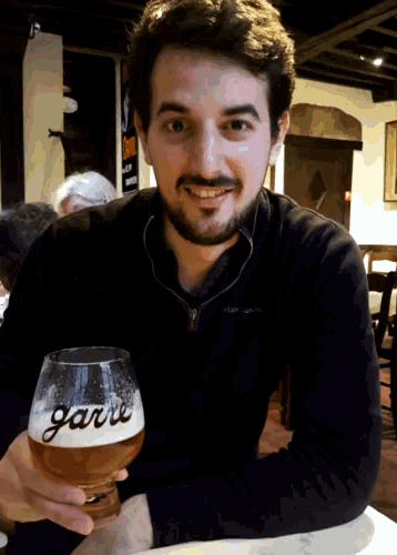 a man holding a glass with the word garni on it