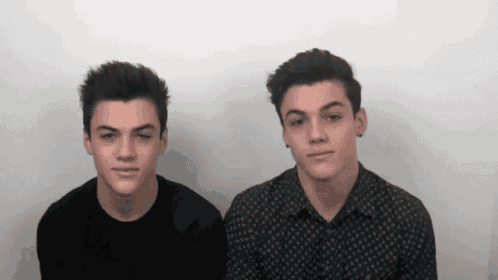 two boys are standing next to each other and looking at the camera