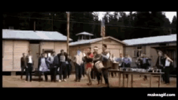 a group of people are dancing in front of a row of buildings