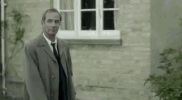 a man in a suit and tie is standing in front of a brick wall .