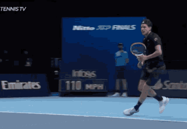 a man is playing tennis in front of an emirates banner