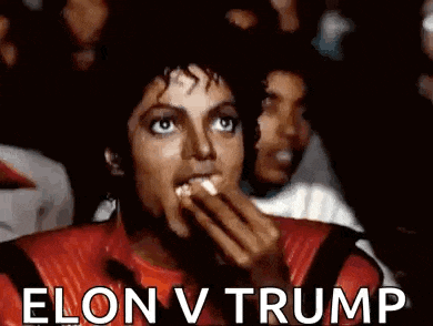 a man in a red jacket is eating popcorn in front of a crowd while watching a movie .