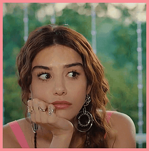a close up of a woman 's face with her hand on her chin and a ring on her finger .