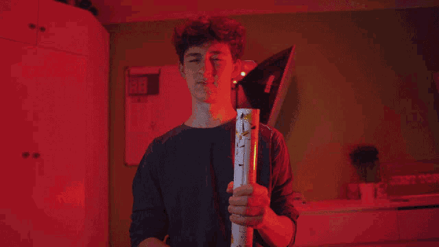 a young man is holding a torch in front of a red wall with a calendar on it
