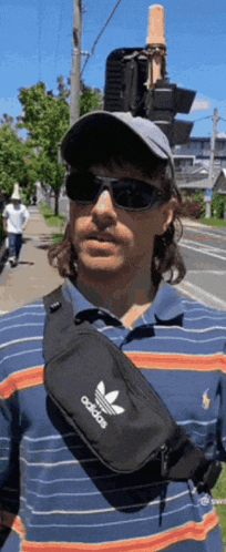 a man wearing sunglasses and a hat has an adidas fanny pack around his waist