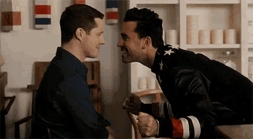two men are looking at each other and one has a jacket with stars on it