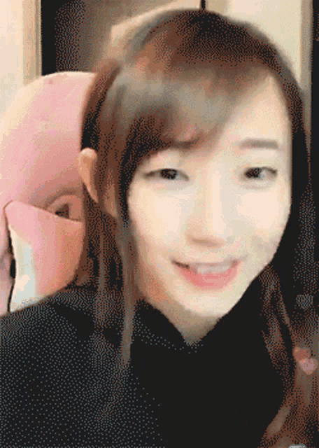 a close up of a woman 's face with a pink stuffed animal in the background