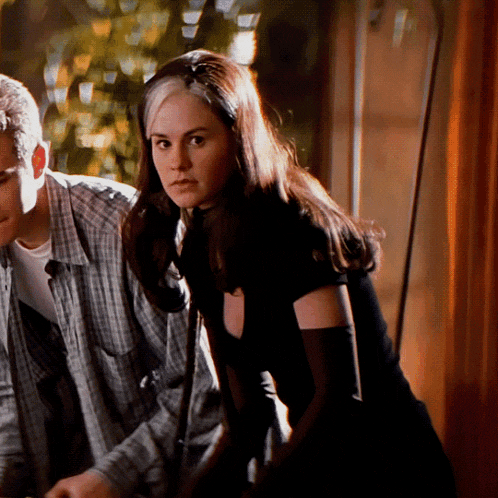 a man in a plaid shirt stands next to a woman in a black top