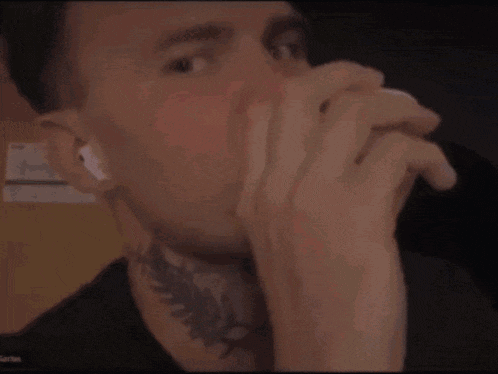 a man with a tattoo on his neck covering his mouth