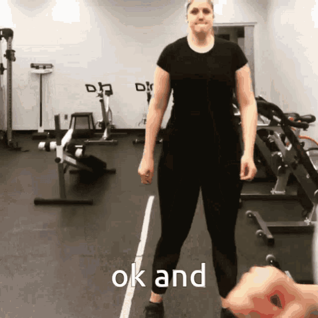 a woman in a black shirt is standing in a gym with the words ok and on the floor