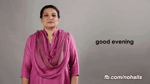 a woman in a pink shirt is making a sign that says `` good evening '' in sign language .