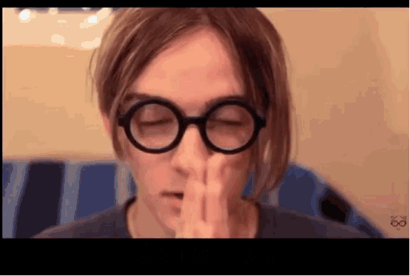a close up of a person wearing glasses covering their mouth