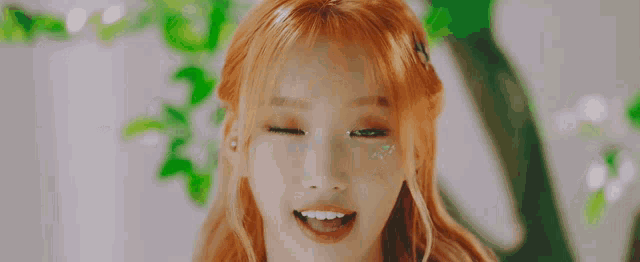a close up of a woman with red hair and green eyes smiling .