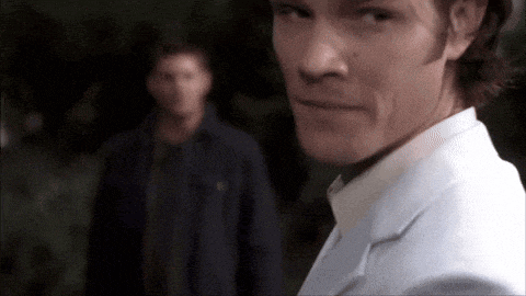 a man in a white suit is looking at the camera