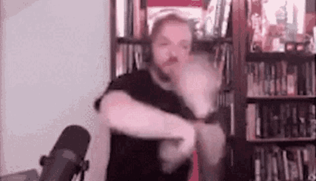 a man with a beard is dancing in front of a microphone in a room .