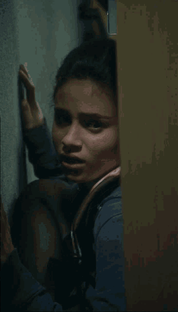 a woman leaning against a wall with her hand on the wall