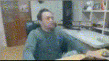 a man in a blue sweater is sitting at a desk